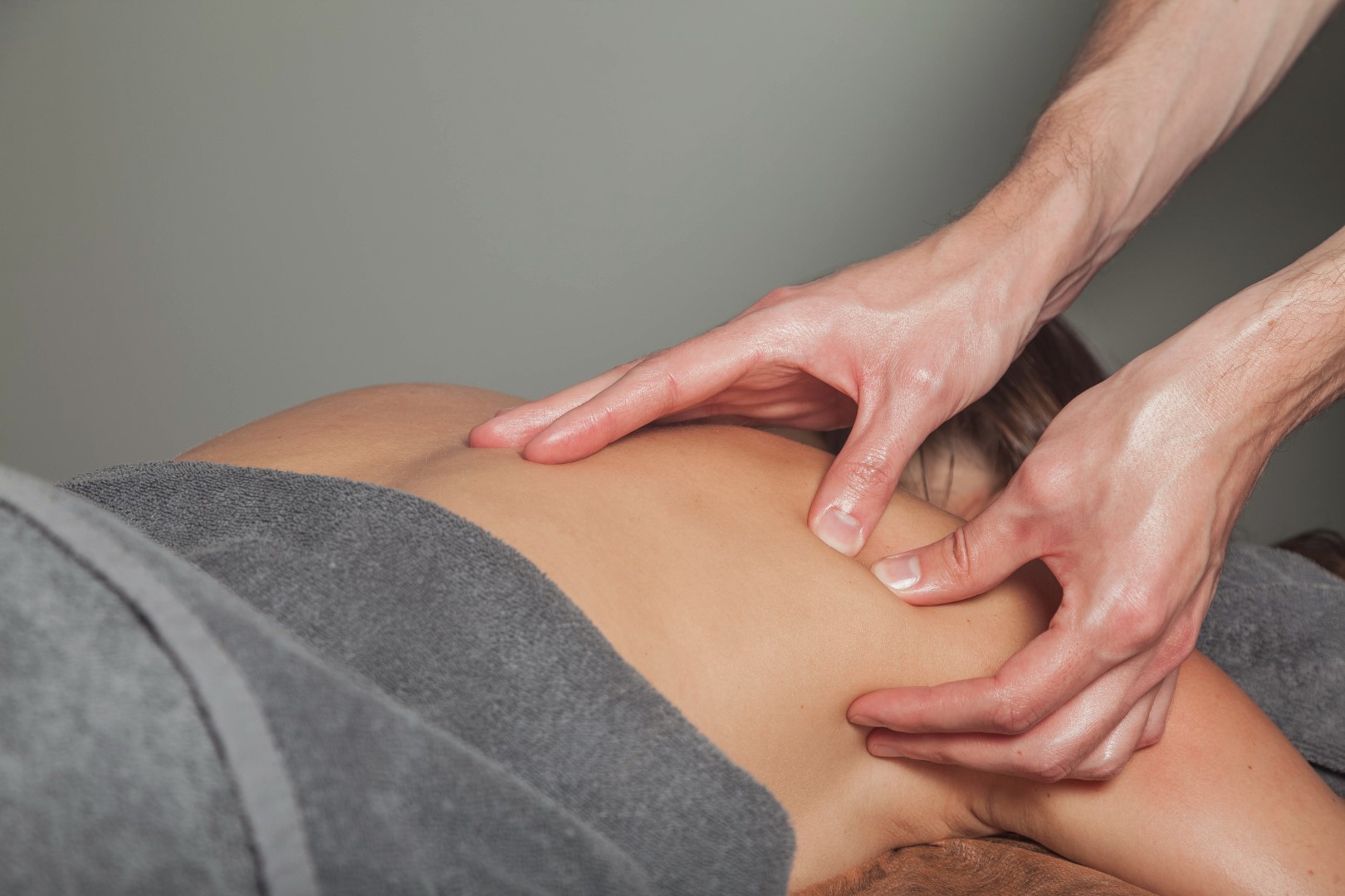 Young woman enjoys sports wellness massage in medical office of fitness room